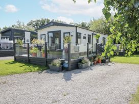 A mobile home with a deck and plants at Lilac Lodge in Carnforth