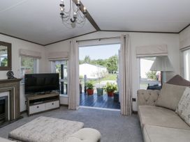 A living room with a television and sofa at Lilac Lodge in Carnforth