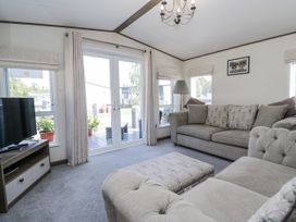 A living room featuring a sofa and television at Lilac Lodge in Carnforth