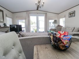 A living room with a television and a basket of candies at Lilac Lodge in Carnforth