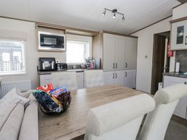 A kitchen with appliances and dining area at Lilac Lodge Carnforth
