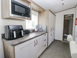 A kitchen with appliances and cabinets at Lilac Lodge Carnforth