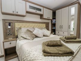 A bedroom featuring a bed with pillows and towels at Lilac Lodge Carnforth
