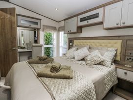 A bedroom with a bed and chair at Lilac Lodge Carnforth