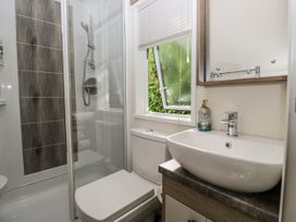 A bathroom featuring a shower, toilet, and sink at Lilac Lodge in Carnforth