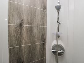 A shower area with a showerhead and tiled wall at Lilac Lodge in Carnforth