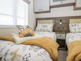 A bedroom with two beds and a window at Lilac Lodge in Carnforth
