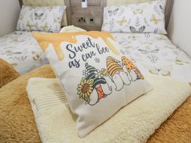 A bedroom with a decorative pillow and patterned bedding at Lilac Lodge in Carnforth