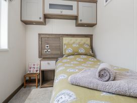 A bedroom with a single bed and nightstand at Lilac Lodge in Carnforth