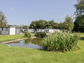 An outdoor area with holiday lodges and a pond at Lilac Lodge in Carnforth