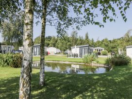 An outdoor area with trees and a pond at Lilac Lodge in Carnforth