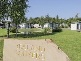 An outdoor area with a lodge and a pond at Yealand Conyers in Carnforth