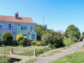 A semi detached house with a small garden and a path with a footbridge in front of it at Beck View in Sheringham