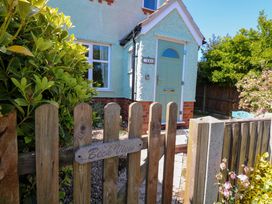 A wooden gate with a Beck View sign leading to a small house with a light blue door and green plants in Sheringham