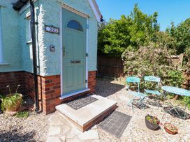 A front porch with a green door and two metal chairs and a table in a garden at Beck View in Sheringham