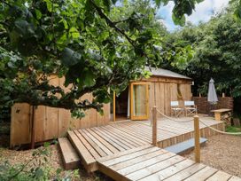 A wooden cabin with a deck and outdoor seating at Brambly Cabin in Crediton