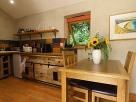 A kitchen with wooden furniture and flowers at Brambly Cabin in Crediton