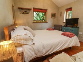 A bedroom with a bed, chair, and television at Brambly Cabin in Crediton