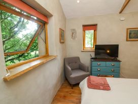 A bedroom with a television and an armchair at Brambly Cabin Crediton
