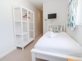 A bedroom with a bed, shelf, and television at Foundry Cottage In Hayle Harbour, Hayle