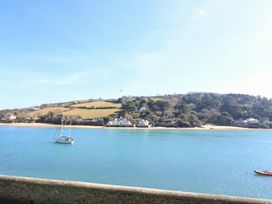 A view of a sailing boat on water with houses and hills at Waders in Salcombe