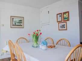 A dining room with a table, chairs, and a vase of tulips at Waders in Salcombe