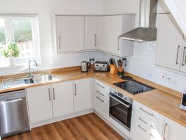 A kitchen with a sink, kettle, toaster, and cooktop at Waders in Salcombe