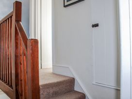 A staircase with a wooden handrail and a door at Waders in Salcombe