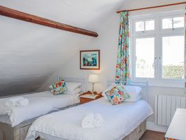 A bedroom with two beds, a lamp and a window at Waders in Salcombe