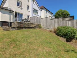A garden with grass and patio seating at Waders Salcombe