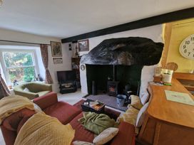 A living room with a wood burning stove a red sofa a green armchair and a window at Quarry Cottage in Blaenau Ffestiniog
