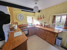A kitchen with wooden countertops and cabinets a wall clock and copper pans hanging on the wall at Quarry Cottage in Blaenau Ffestiniog