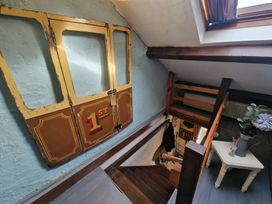 A stairway with wooden steps and a small table with flowers beside a skylight window at Quarry Cottage in Blaenau Ffestiniog