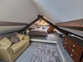 An attic bedroom with a bed sofa rug and chest of drawers at Quarry Cottage in Blaenau Ffestiniog