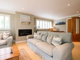 A living room with a sofa, armchair, coffee table, and fireplace at Welsummer in Salcombe