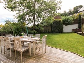 A garden with a wooden table and chairs at Welsummer in Salcombe