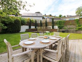 A garden with a wooden dining table and chairs at Welsummer in Salcombe