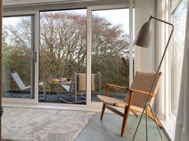 A sunroom with a chair and a lamp at Estuary Watch Lelant near Carbis Bay