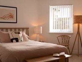 A bedroom with a bed, lamp, chair, and table at Estuary Watch in Lelant near Carbis Bay