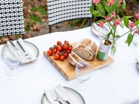 An outdoor dining table with bread, tomatoes, and a flower arrangement at Estuary Watch Lelant near Carbis Bay