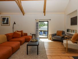 A living room with orange and gray seating wooden beams and a black coffee table at 3 Caddaford Barns in Buckfastleigh