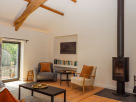 A living room with two armchairs a wood stove and a bookshelf at 3 Caddaford Barns in Buckfastleigh