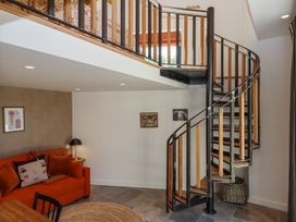 A room with a spiral staircase orange sofa and wall art at 3 Caddaford Barns in Buckfastleigh
