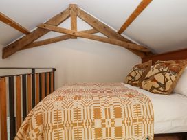 A bedroom loft with a bed a patterned blanket and two decorative pillows at 3 Caddaford Barns in Buckfastleigh