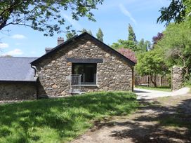 A stone house with a slate roof surrounded by trees and grass at 3 Caddaford Barns in Buckfastleigh
