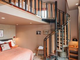 A bedroom with a spiral staircase and a bed at 3 Caddaford Barns in Buckfastleigh