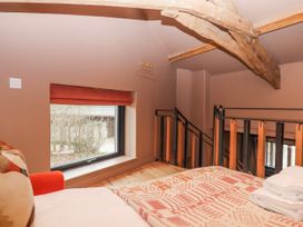 A loft space with a bed and window at 3 Caddaford Barns Buckfastleigh