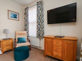 A living room with a television and armchair at 50 West Street Edelweiss in Scarborough