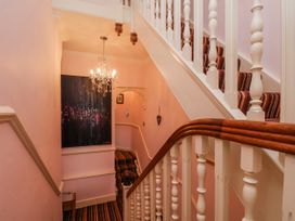 A staircase with a chandelier and artwork in a hallway at 50 West Street Edelweiss Scarborough