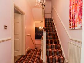 A hallway with a staircase and chandelier at 50 West Street Edelweiss in Scarborough
